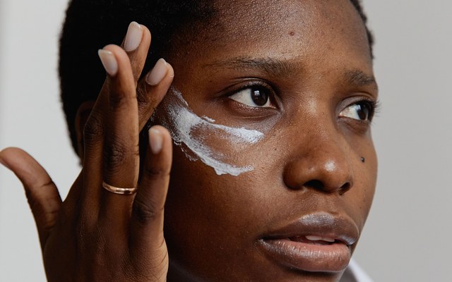 Femme appliquant une crème de soin sur sa joue