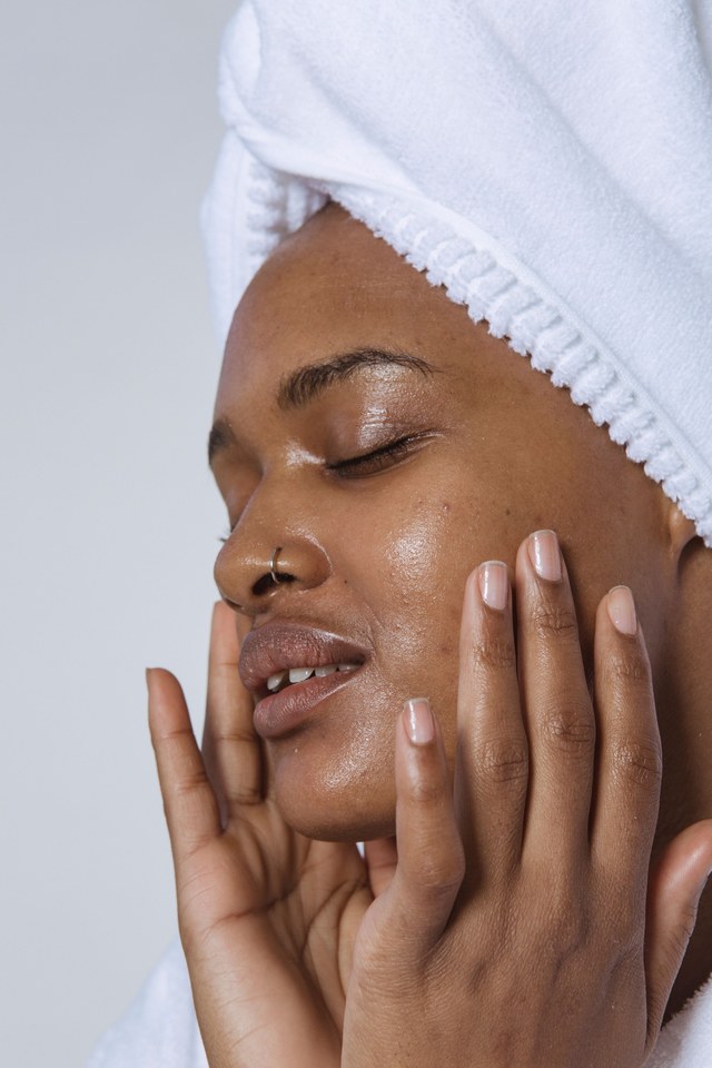 Femme en serviette blanche massant doucement ses joues